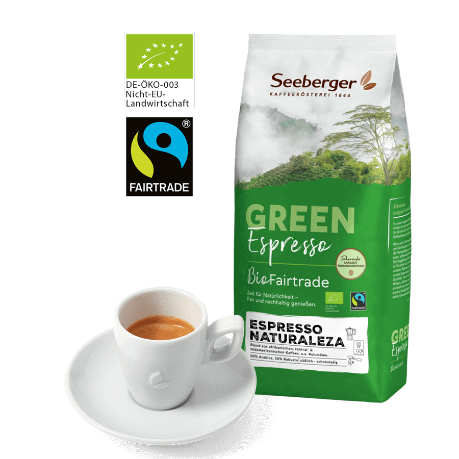 Espresso in einer weißen Porzellan Espressotasse mit Untertasse. Daneben eine 1kg-Packung Seeberger Bio Fairtrade Espresso Naturaleza